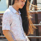 A close-up view of a man wearing the Green Love Paisley shirt, capturing the intricate paisley print and subtle pastel hues. The shirt features a relaxed fit and a pointed collar, styled with the sleeves casually rolled up. His long, wind-touched hair adds a sense of movement to the image, emphasizing the lightweight fabric of the shirt.